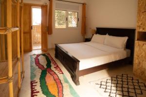 a bedroom with a bed and a window and a rug at Namaste Lodge Experience in Taghazout +90 photos