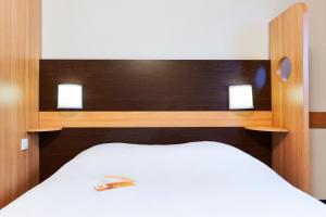 um quarto com uma cama branca com duas luzes em Première Classe Annemasse Ville La Grand em Ville-la-Grand