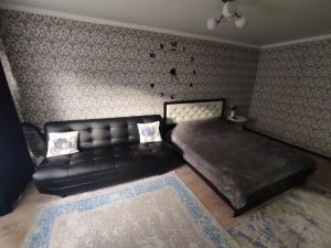 1 dormitorio con sofá de cuero negro y cama en Квартира посуточно в Шахтинске, en Shakhtīnsk