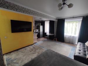 sala de estar con TV en una pared amarilla en Квартира посуточно в Шахтинске, en Shakhtīnsk
