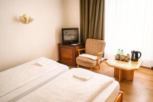 Habitación de hotel con 2 camas, silla y TV en HOTEL Am Ratshof, en Halle an der Saale