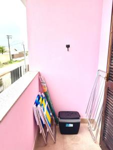 a balcony with a pink wall and a trash can at Apartamento à beira-mar Ilha Comprida in Ilha Comprida