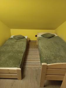 two beds in a room with yellow walls at Beskidzki Zakątek in Żabnica