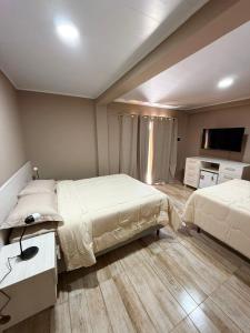 a bedroom with two beds and a flat screen tv at Hotel SMA in Puerto Iguazú +16 photos