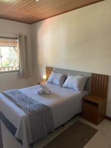 a bedroom with a bed with white sheets and a window at Aconchego da Serra in Nova Friburgo