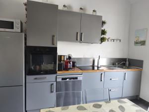 a kitchen with white cabinets and stainless steel appliances at La maison d Adélaïde in Saint-Laurent-dʼAigouze