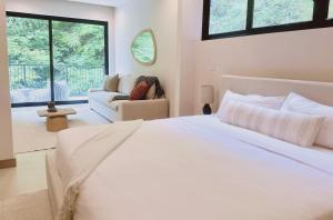 a white bedroom with a large bed and a couch at Brisa del Valle at Naumi, Ocean Views & Beach Club in Coco