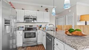a kitchen with white cabinets and granite counter tops at Cozy 3-Bedroom Condo - Comfy Living Space Two Balconies Outdoor Pool Beach Walkable - Score up to 450 Every Day in Tickets for Local Activities in Romar Beach