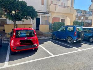 a red car and a blue car parked in a parking lot at Affittacamere La bottega del barbiere in Scalea
