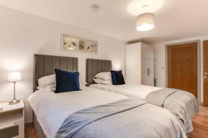 two beds with blue pillows in a bedroom at Vine Cottage in West Runton