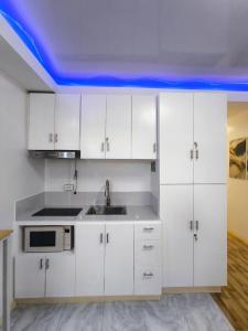 a kitchen with white cabinets and a blue ceiling at AMS Apartment in Butuan