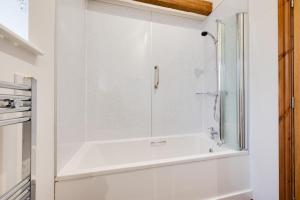 a white bathroom with a shower and a sink at The Dairy in Quidenham