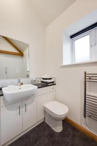 a white bathroom with a toilet and a sink at The Dairy in Quidenham