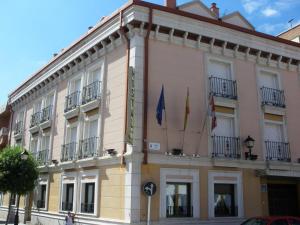 un edificio con dos banderas delante en Hostal Virgen del Villar en Laguna de Duero