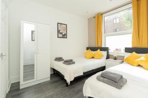 Un dormitorio con dos camas y un espejo. en Open Mind Property - Stylish 4BR House with 7 Beds, en Portsmouth