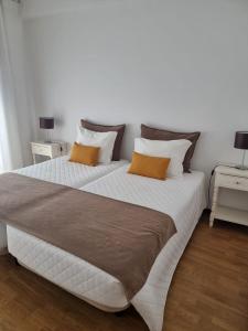 a large white bed with two orange pillows on it at Casa Dos Arcos in Aveiro