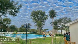 a swimming pool at a park with people standing around it at Cabañas Camping Malvinas Argentinas Paso de la Patria in Paso de la Patria