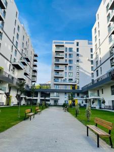 eine Reihe von Bänken in einem Park mit hohen Gebäuden in der Unterkunft Studio Satina Residence with Private Parking & Self Check-In in Craiova