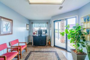 a waiting room with red chairs and a door with a plant at Capital O Aurora Inn Monett US 60 in Aurora