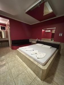 Una cama grande en una habitación con una pared roja. en Motel Ladakk, en Brasilia