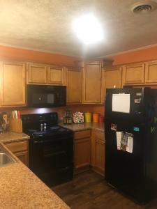 a kitchen with a black refrigerator and wooden cabinets at Middle of It All only 30 min from Mammoth Cave! in Bowling Green