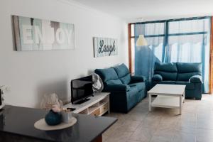 a living room with blue couches and a tv at Estancia - Bungalow en Puerto Rico in Puerto Rico de Gran Canaria