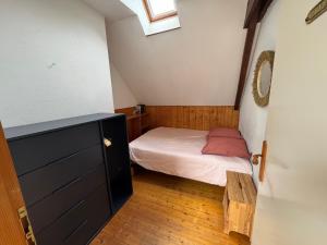 a small bedroom with a bed and a window at Charmant penty avec cheminée in Sainte-Hélène