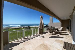 Un balcón con sombrilla y vista al mar. en Jeffreys Bay Beach Accommodation Waters Edge, en Jeffreys Bay