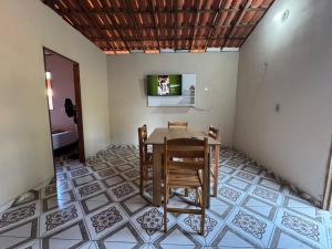 a dining room with a table and chairs and a television at Casa Sereia Guriu in Guriú +3 photos