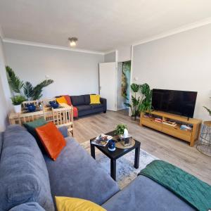 a living room with a blue couch and a tv at NEW, Refurbished Modern & Spacious 1 Bed Flat Westfield Shepherd's Bush Free Wi-Fi Super King Bed in London