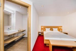 a bedroom with a bed and a bathroom with a sink at Pension Gabl in Pfunds