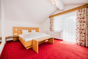 a bedroom with a bed and a red carpet at Pension Gabl in Pfunds
