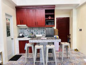 a kitchen with red cabinets and a counter with stools at Casita ni Raphaella in Tacloban