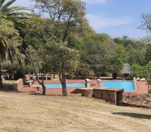 ein Schwimmbad in einem Park mit Bäumen in der Unterkunft Indabuch in Rustenburg