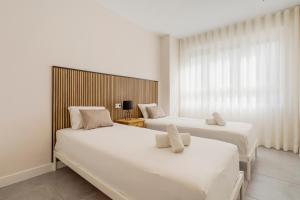 two white beds in a room with a window at Luxury 3 BR Apartment with Terrace, pool & gym in Mijas Costa +13 photos