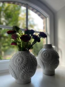 two white vases with flowers sitting on a window sill at Seeidyll an der Wublitz in Werder