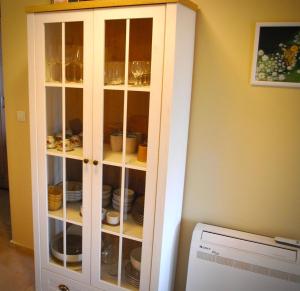 a white cabinet with plates and dishes in it at Къща за гости Белора in Dryanovo +43 photos