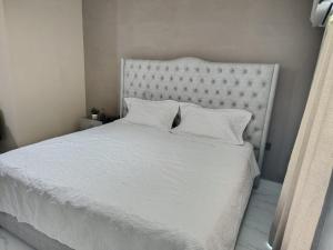 un letto bianco con lenzuola e cuscini bianchi di Laureles del parque loft a Barranquilla
