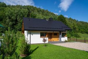 a small white house with a mountain in the background at Domek na Duzynie in Ochotnica Górna