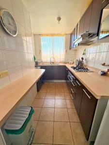 a kitchen with a counter and a clock on the wall at Departamento Costa Manantiales 152 in Concón