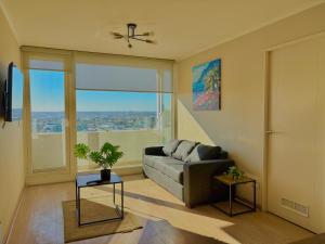 a living room with a couch and a large window at Departamento 3 piezas Centro Chillan - Parking - Vista in Chillán