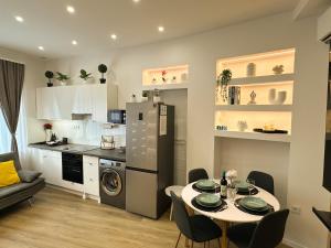 a kitchen and a dining room with a table and a kitchen with a refrigerator at VIBE S33 Apartman Modern & Prémium in Székesfehérvár