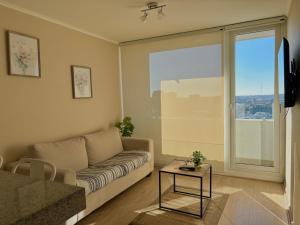 a living room with a couch and a large window at Departamento Centro Chillan - Parking -Vista in Chillán