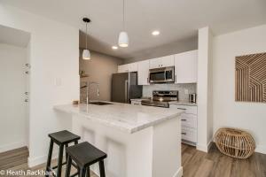 eine Küche mit weißen Schränken und einer Theke mit Stühlen in der Unterkunft 3bd Condo Near Old Town King Bed in Scottsdale