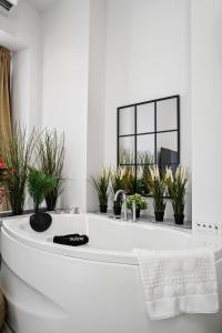 a white bath tub with potted plants in a bathroom at Joy Social Apartment in Bucharest