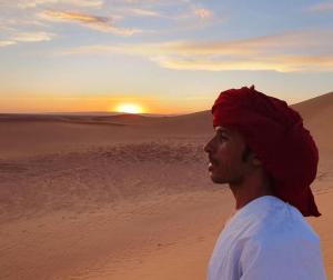 a man in the desert watching the sunset at Planet Camp Désert Tours in Mhamid +9 photos