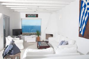 3 Bedroom Cycladic Villa Lia في كالافاتيس: غرفة معيشة بيضاء مع أرائك بيضاء وتلفزيون