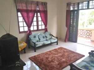 a living room with a couch and two windows at Z&R HOMESTAY in Kota Bharu