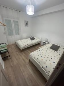 a bedroom with two beds and a chair at Maison Des Vignes in Veyre-Monton