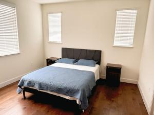 a bedroom with a bed with two night stands and two windows at Cozy Charm Newark Retreat with Free Wifi and AC in Newark